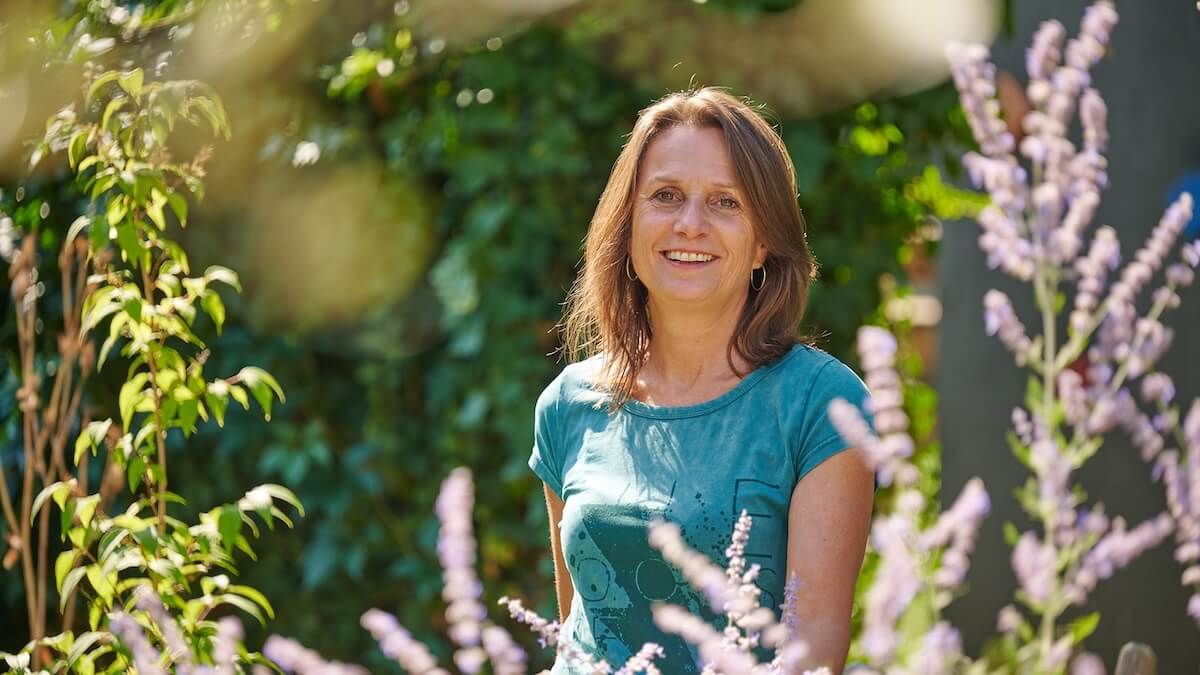Geschäftsführerin Marlis Fahrni im Garten stehend zwischen Blumen und Pflanzen